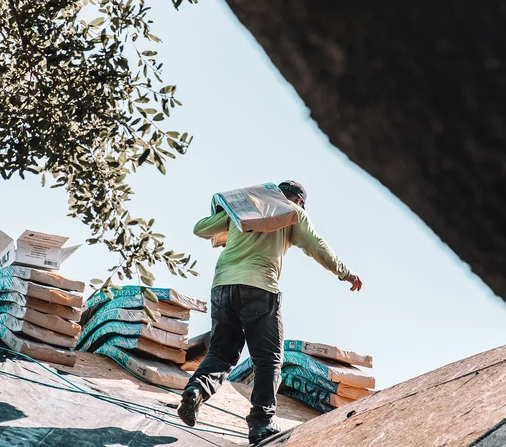 A man is carrying a bag on his back while standing on top of a roof.