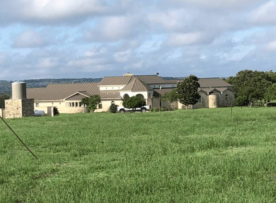 A large house is sitting in the middle of a grassy field