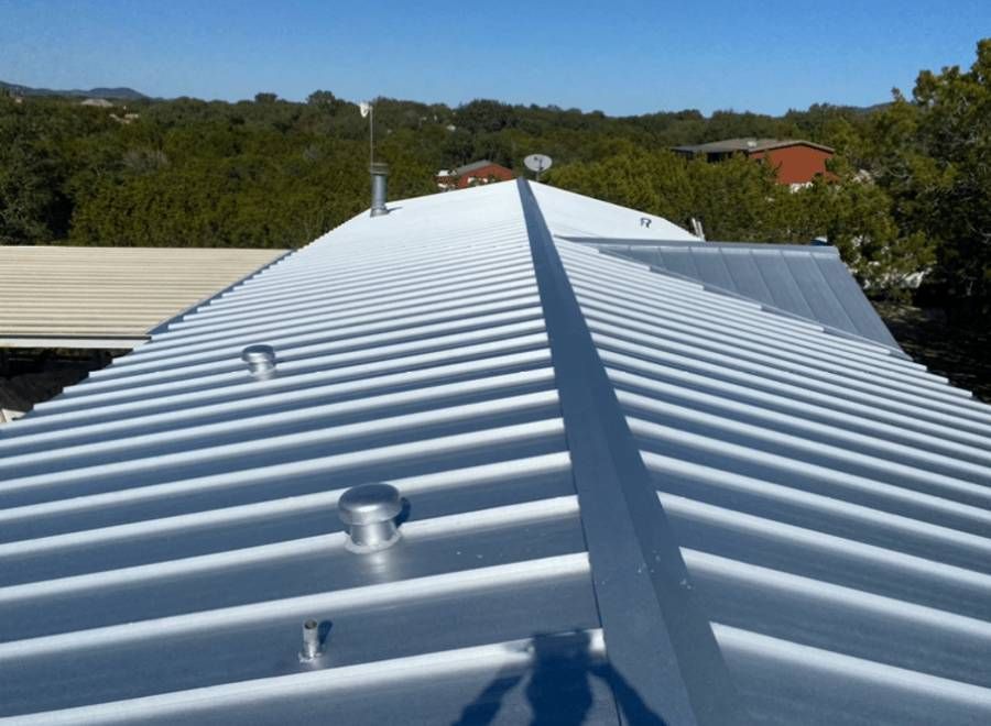 The roof of a building has been painted white and is surrounded by trees