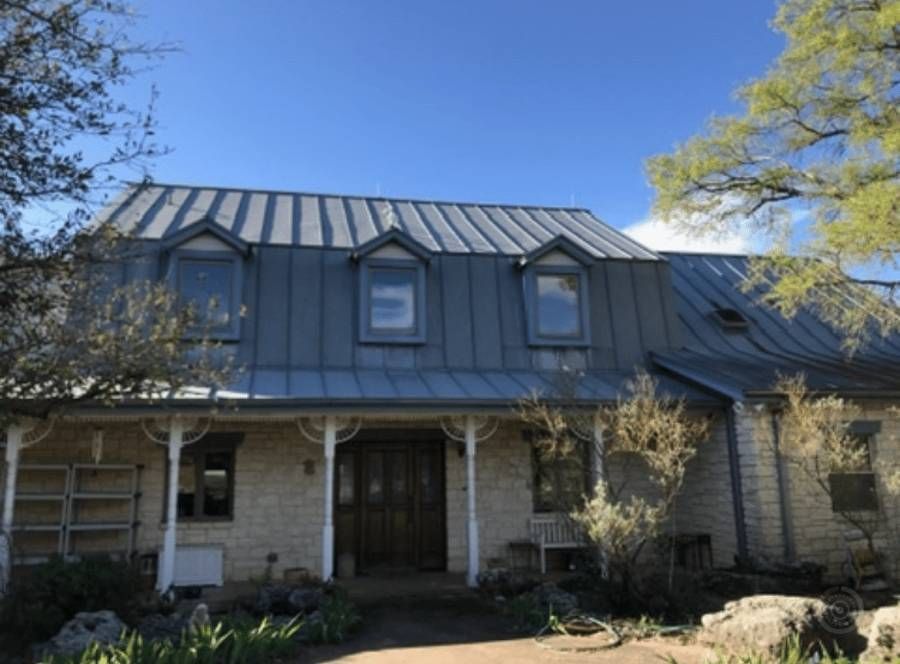 A brick house with a metal roof and a porch