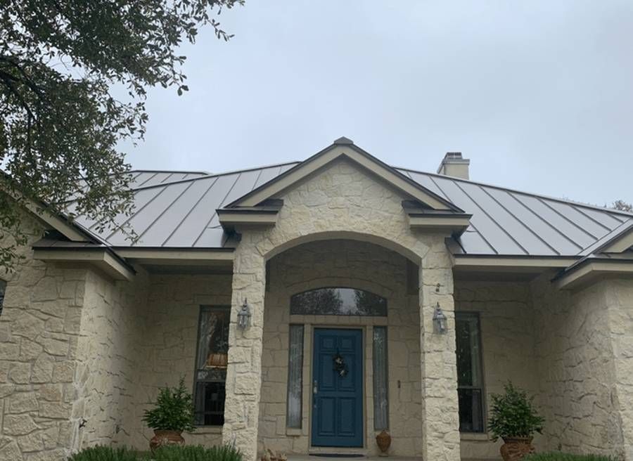 A white house with a blue door and a metal roof