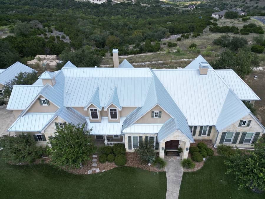 An aerial view of a large house with a white roof