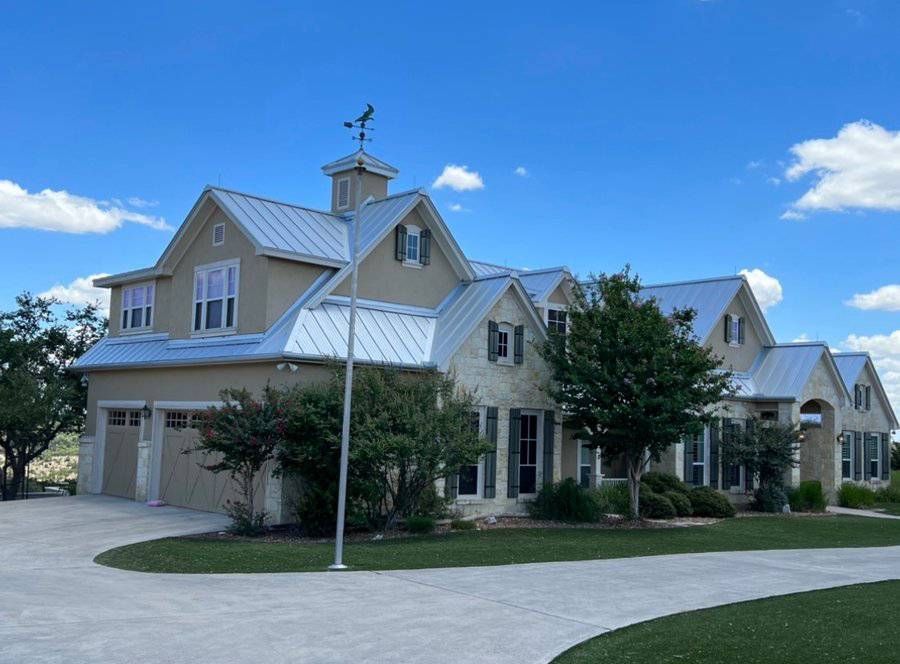 A large house with a metal roof and a weather vane on top