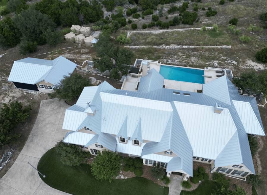 An aerial view of a large white house with a swimming pool