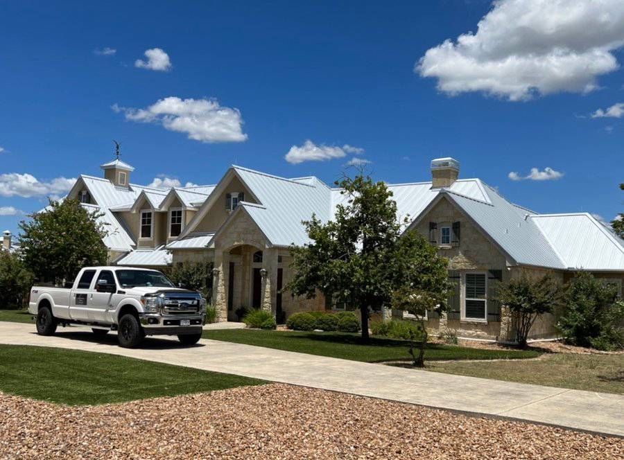A white truck is parked in front of a large house