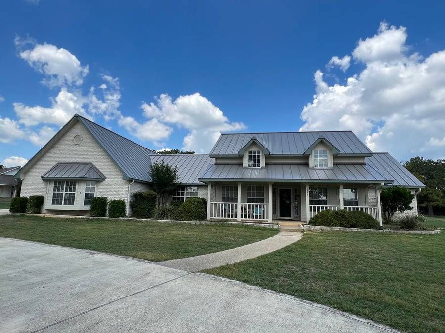 A large white house with a metal roof and a porch