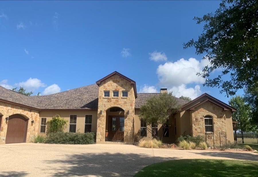 A large stone house with a gray roof is sitting on top of a lush green hillside