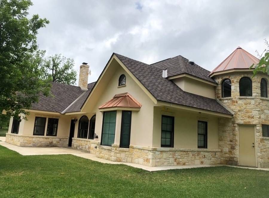 A large house with a copper roof sits in the middle of a lush green field