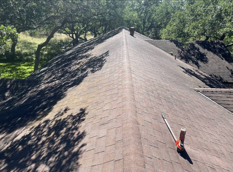 A roof with a chimney on it and trees in the background