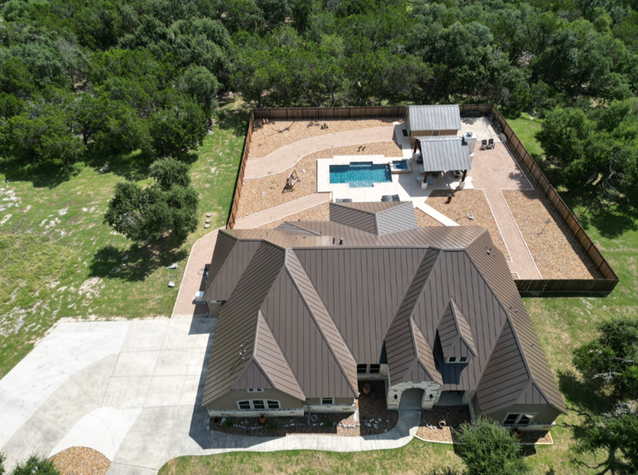 An aerial view of a house with metal roof and a pool in the backyard