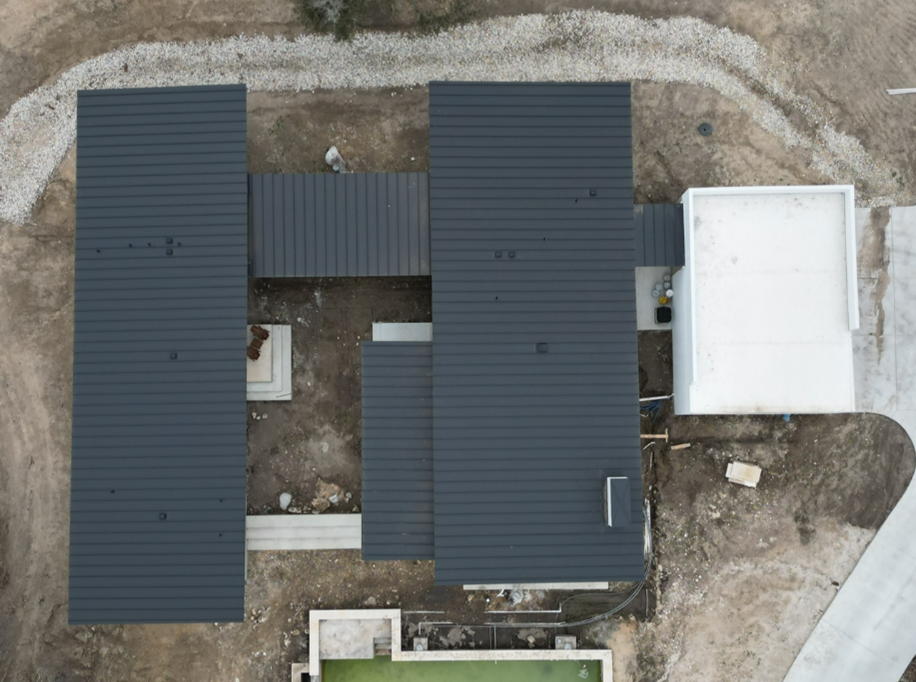 An aerial view of a house under construction with a black metal roof