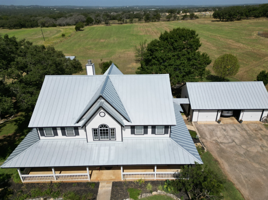 An aerial view of a large white house with a metal roof