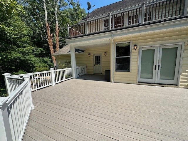 A large deck with a white railing in front of a house.