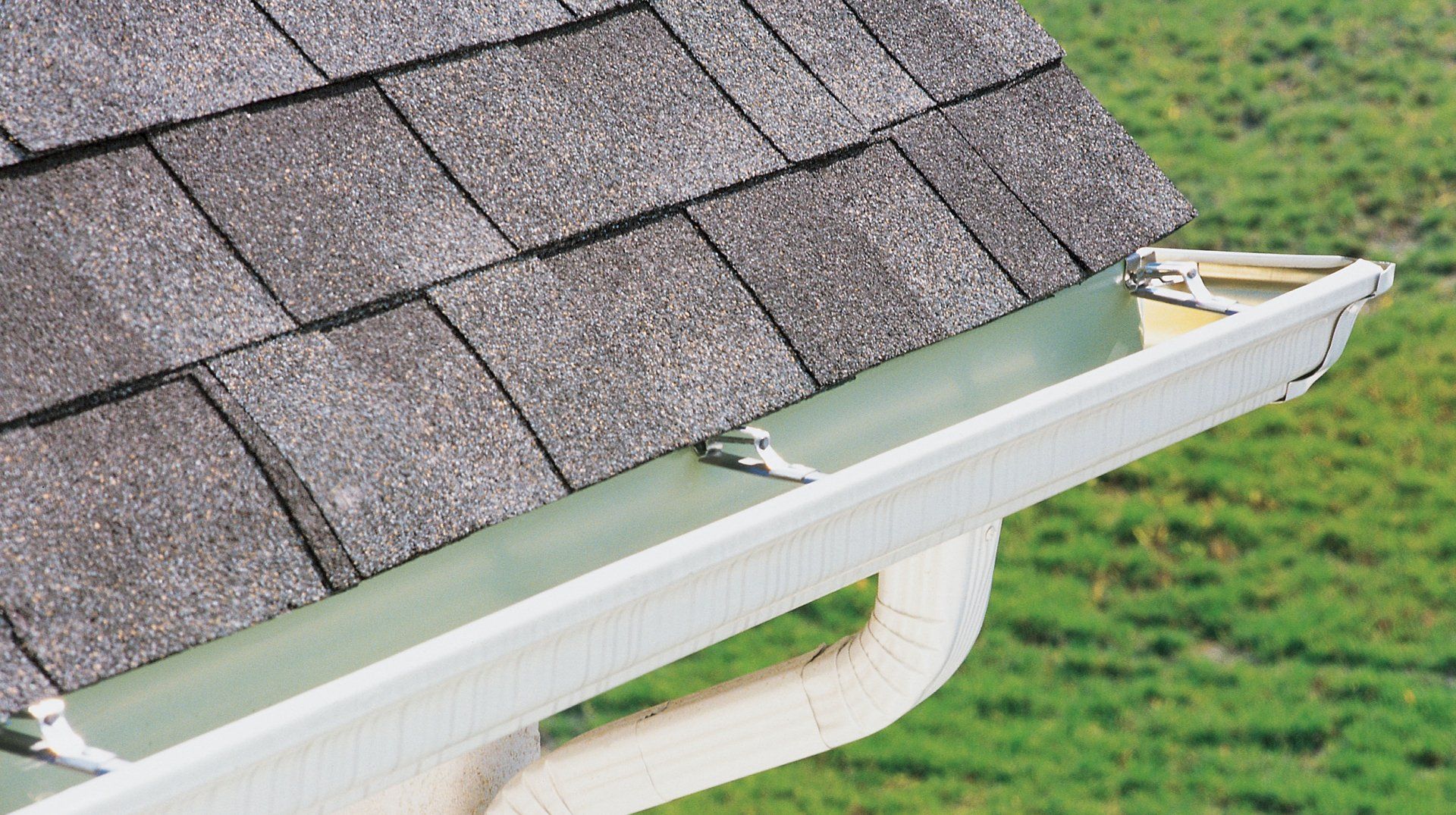 Learn More About Gutters A white gutter is attached to the roof of a house.