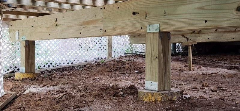 A wooden deck is being built under a house.