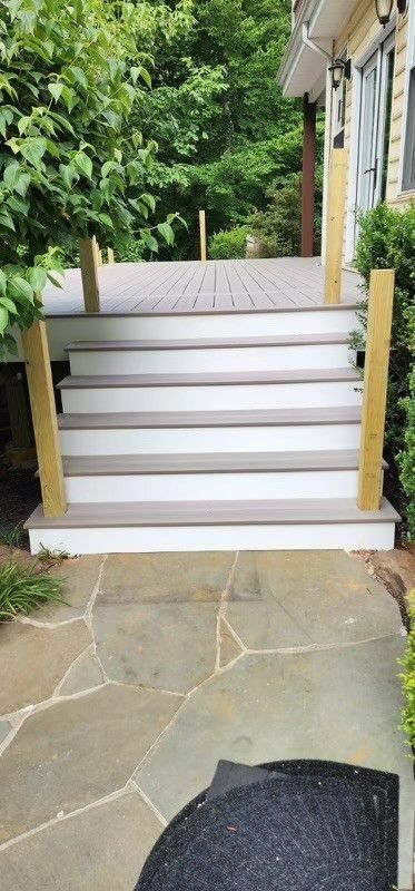 A set of stairs leading up to a deck with trees in the background.