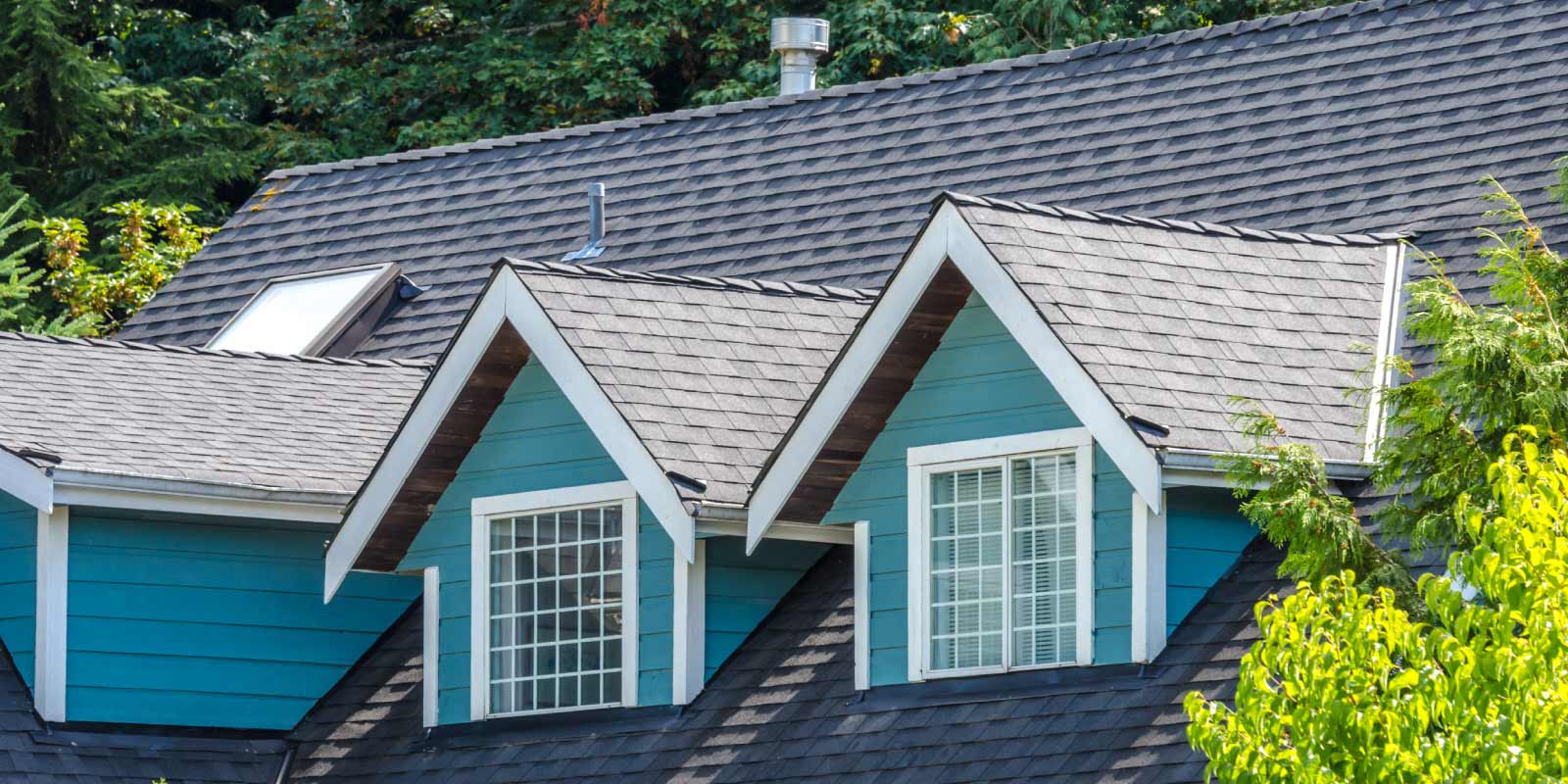 A blue house with a roof that has a skylight on it.
