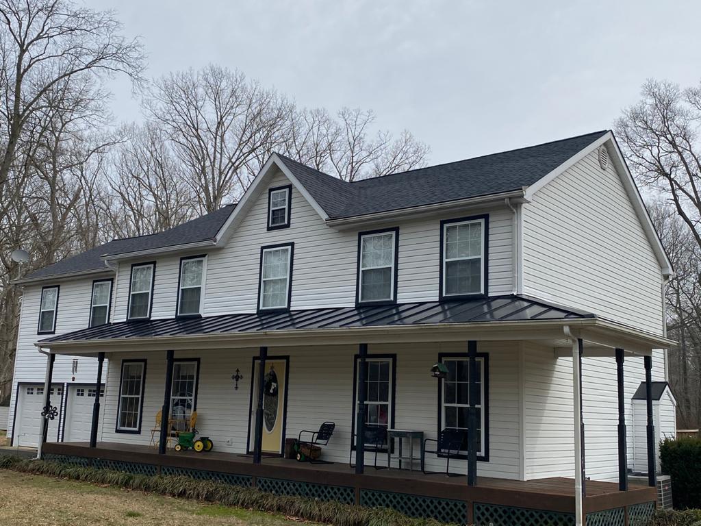 A large white house with a black roof and a porch.