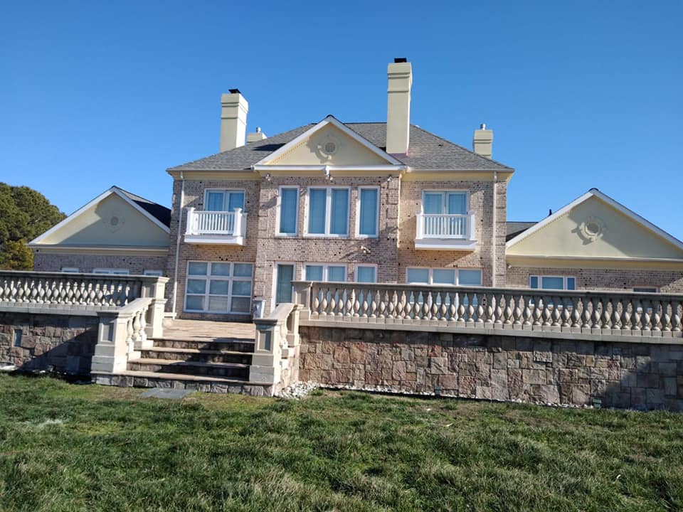 A large house is sitting on top of a grassy hill.