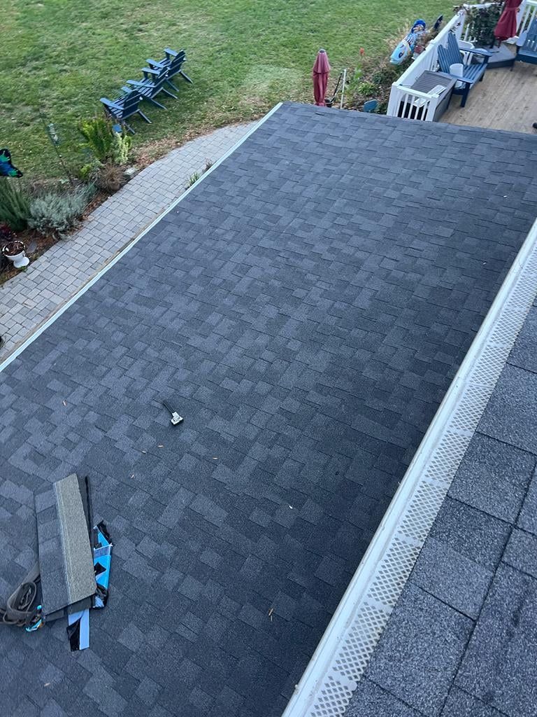 An aerial view of a roof with shingles being installed.