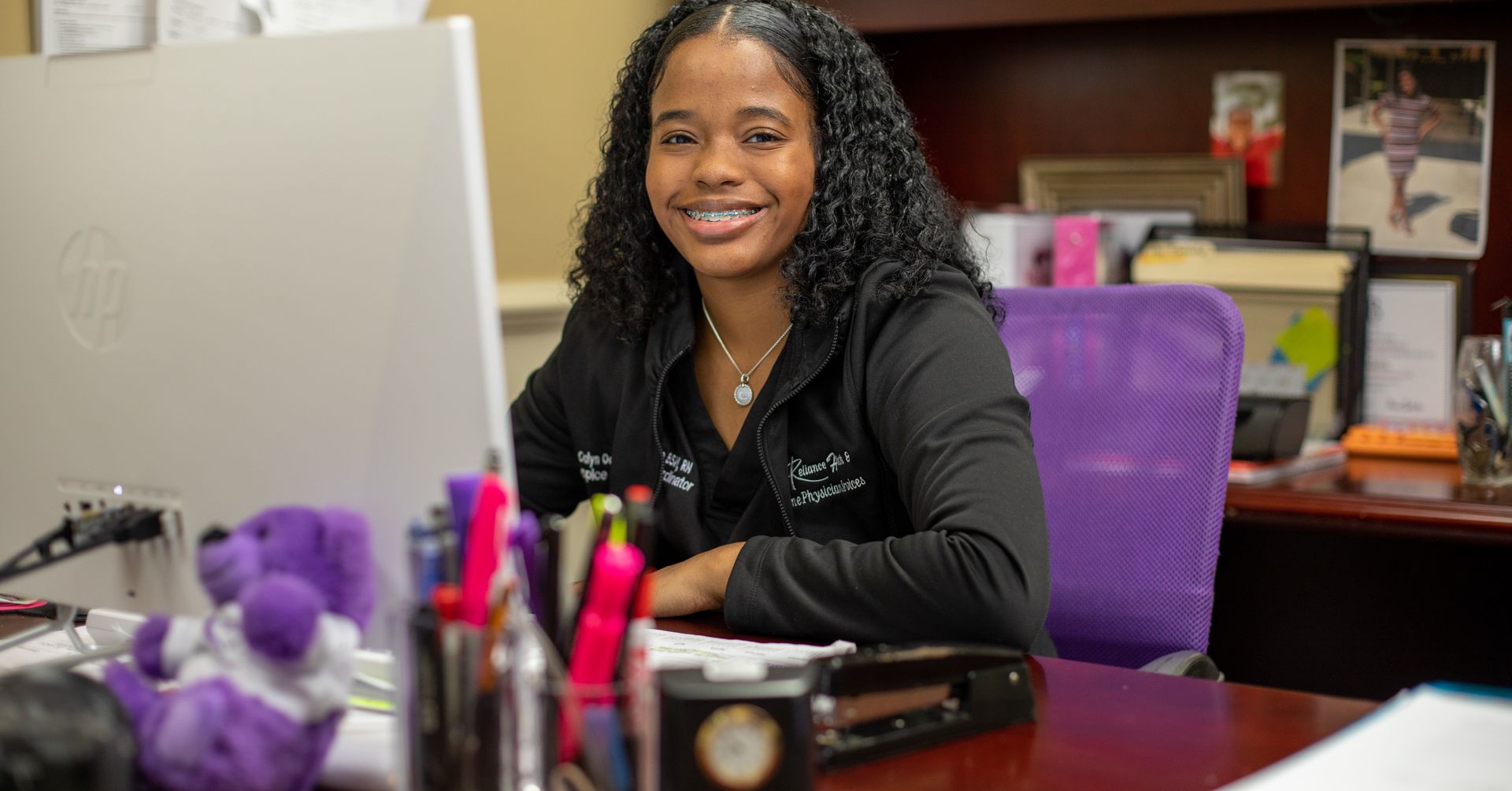 A woman is sitting at a desk in front of a computer.