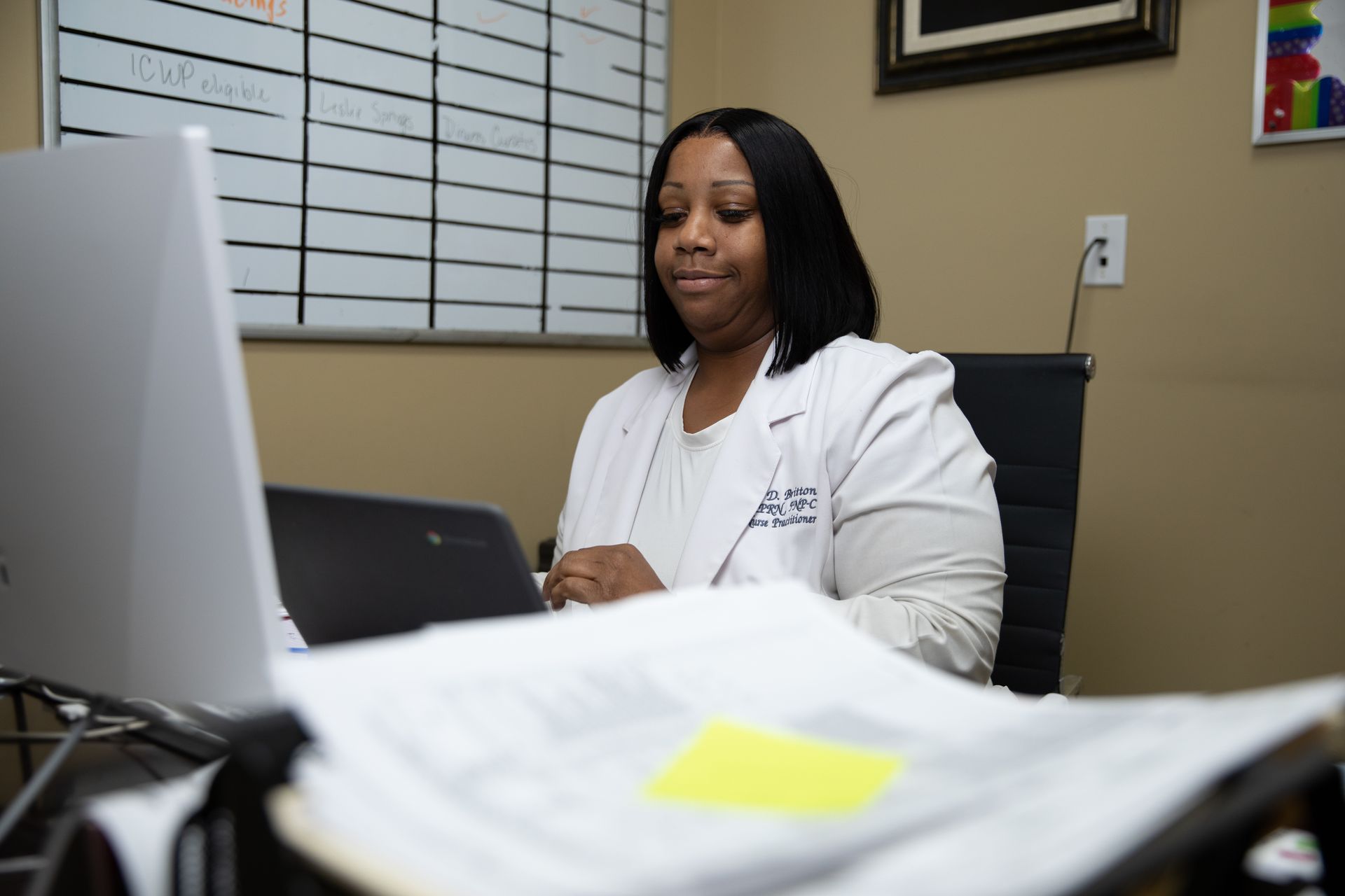 A woman in a lab coat is sitting in front of a laptop computer.