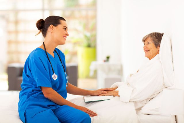 A nurse is holding the hand of an elderly woman in a hospital bed.