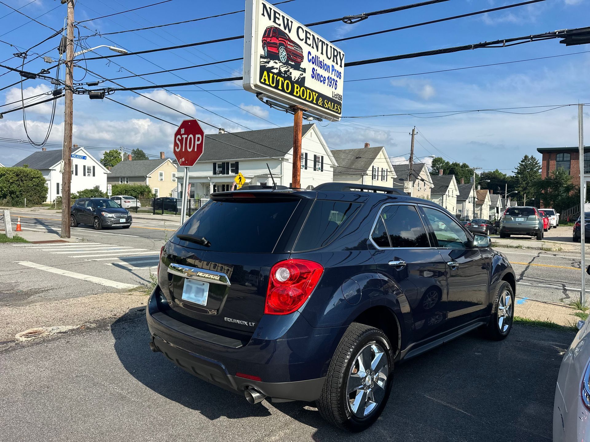 Black SUV at a street intersection near a stop sign and car wash sign on a sunny day