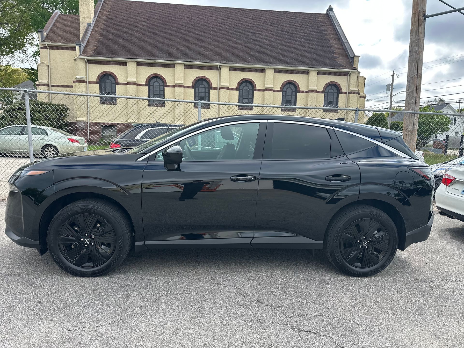 Black SUV parked on a street in front of a stone building, side view