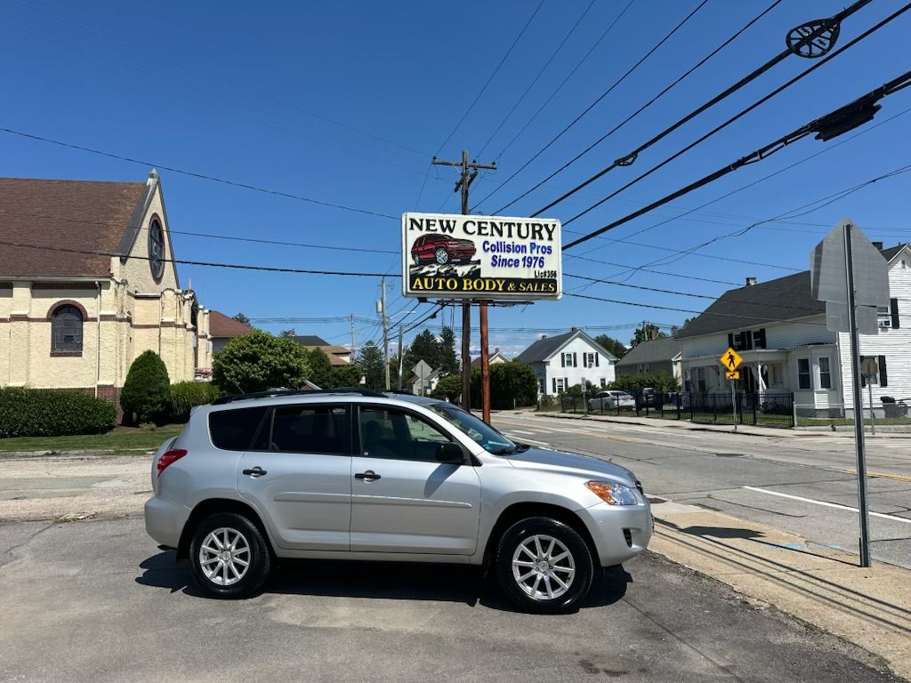 Silver SUV stopped by a roadside sign at a church and houses under a clear blue sky.