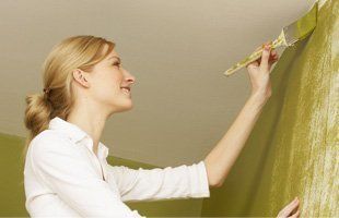 Smiling woman painting on the wall