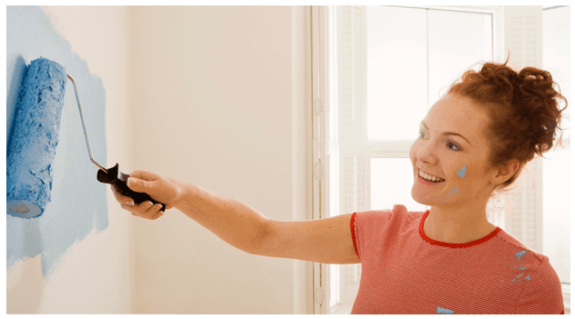 Smiling woman painting on the wall