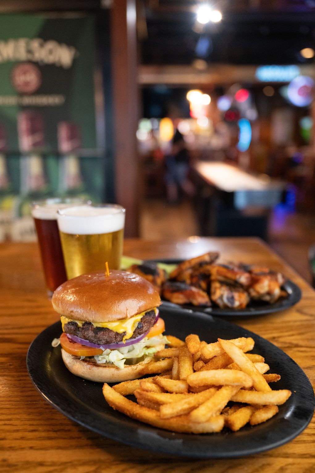 Burger, fries, and beer on a table in a dimly lit restaurant.