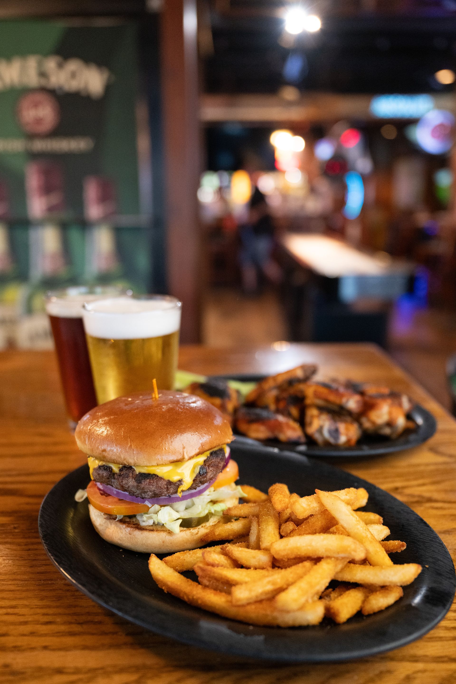 Burger, fries, and beer on a table in a dimly lit restaurant.