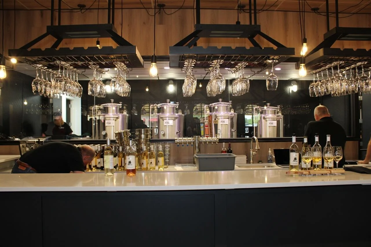Bar with liquor bottles, glasses, and taps; bartenders behind counter.