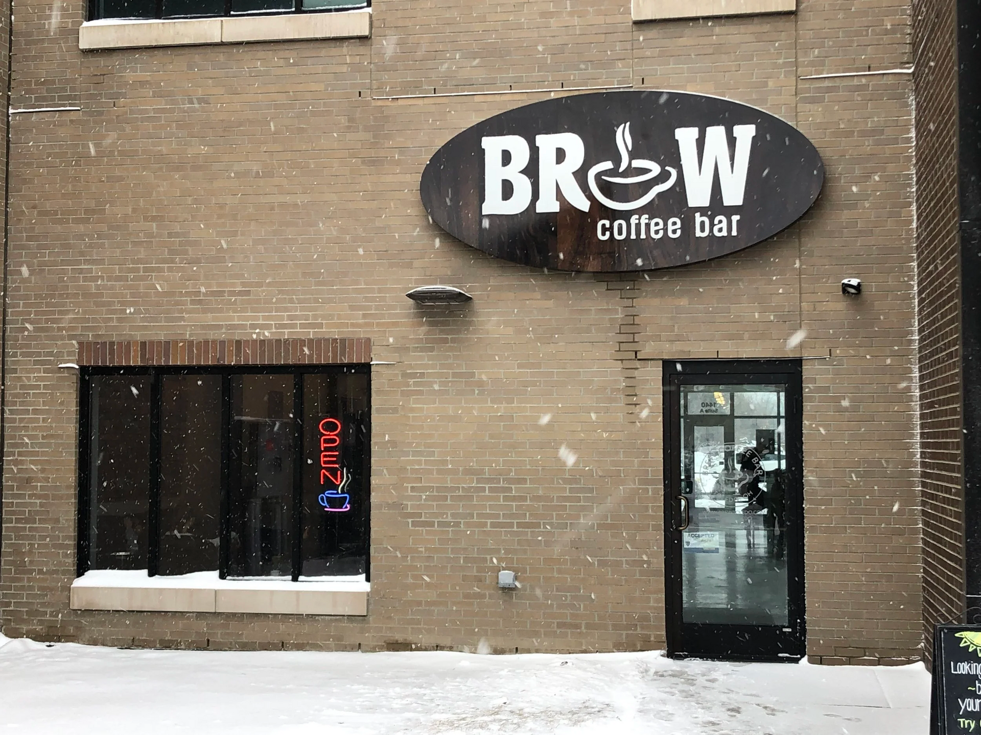 Brew Coffee Bar in snowy setting, with sign, windows, and door.