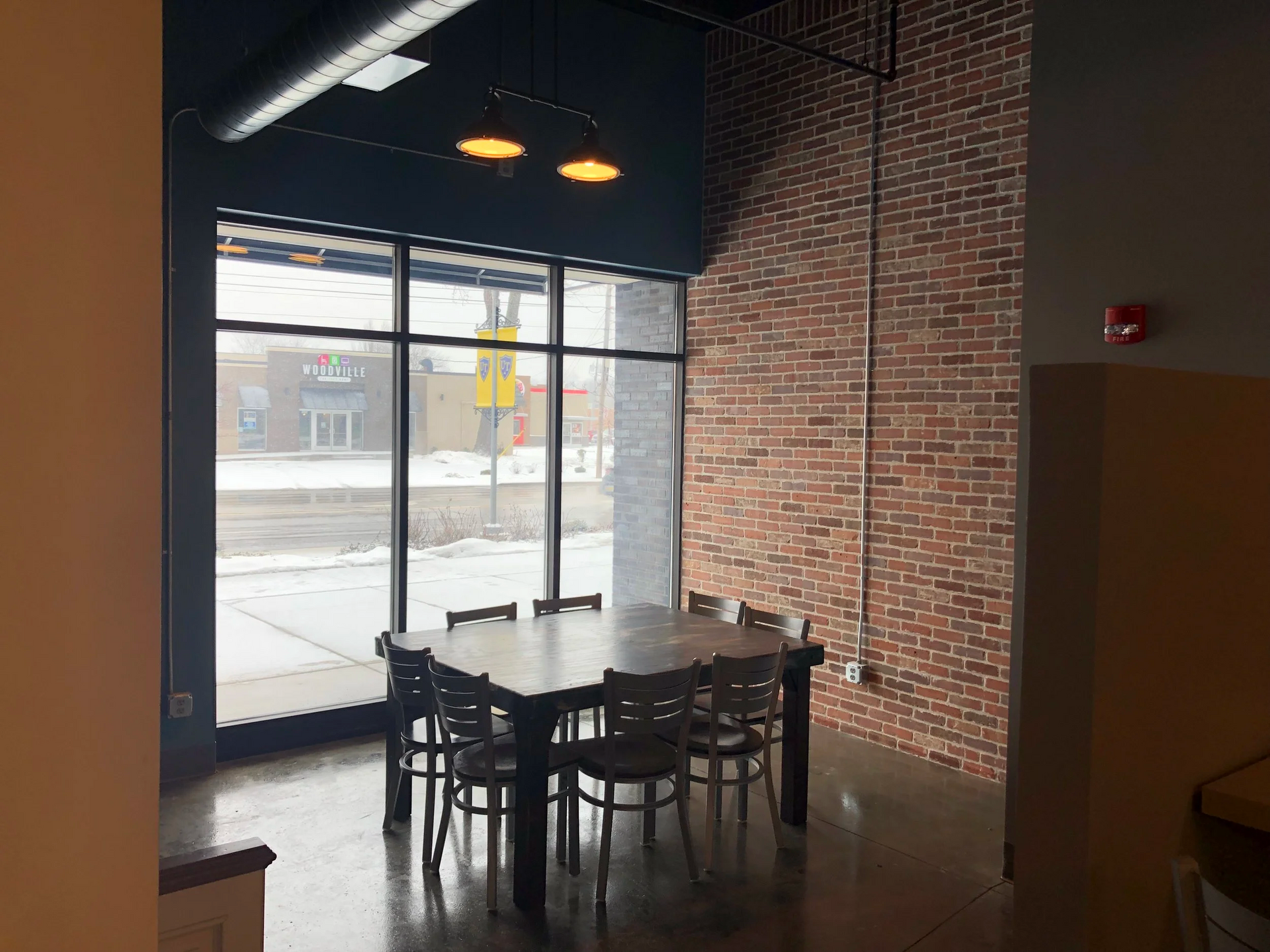 Dining table near large window with brick wall.