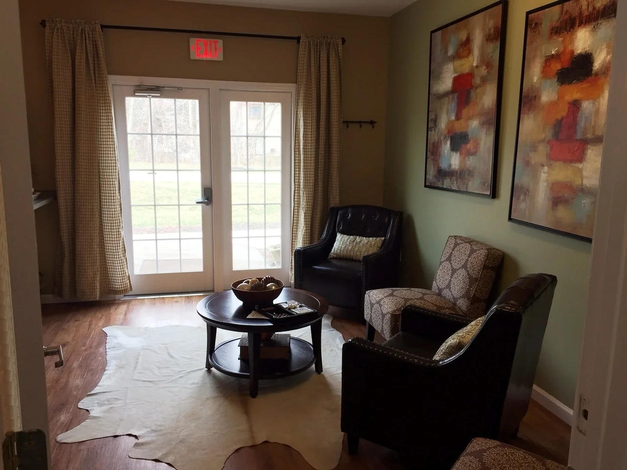 A seating area with armchairs, a coffee table, art, and French doors leading outside.