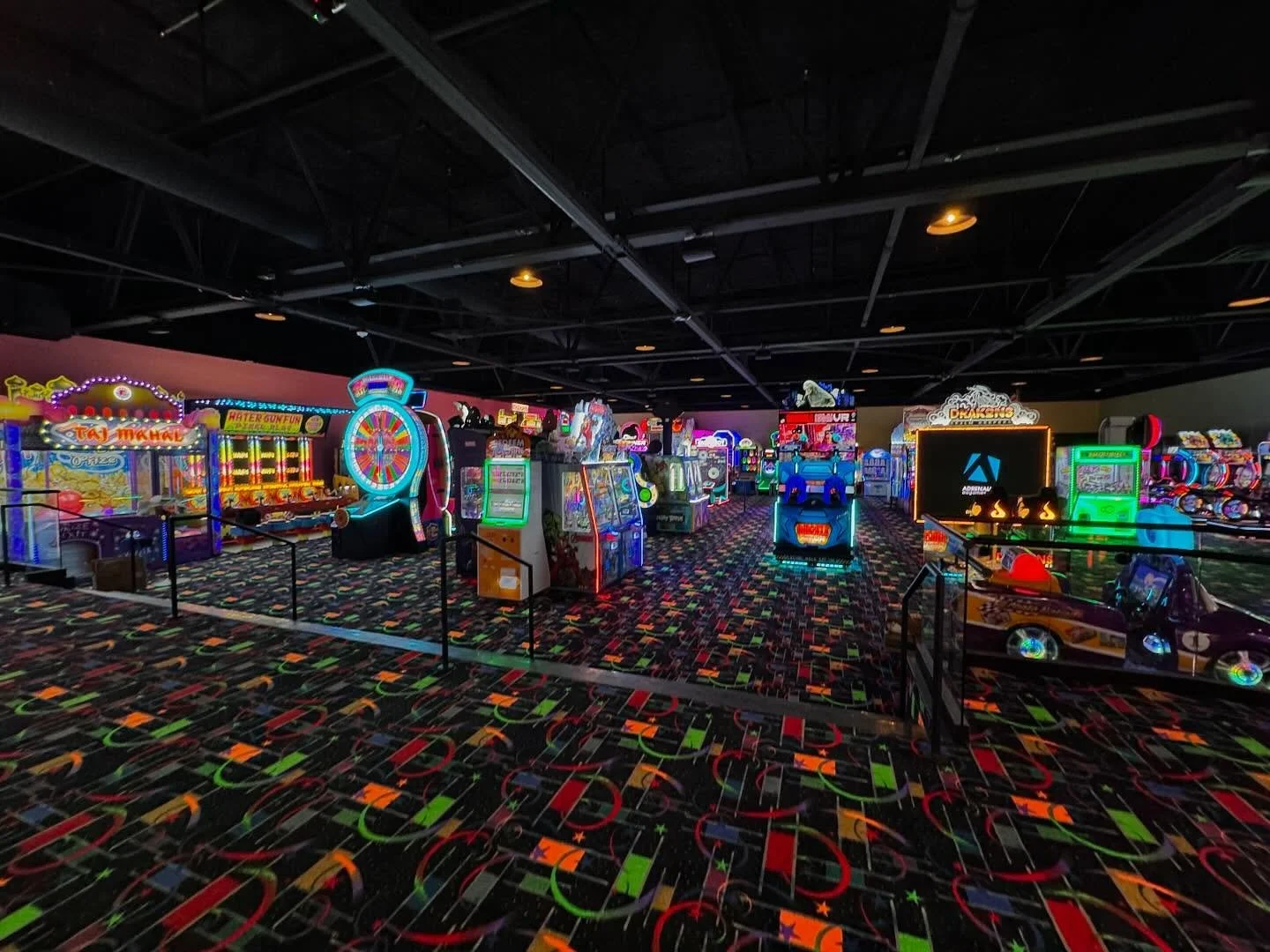 Inside a brightly lit arcade, with colorful games, carpet, and ceiling fixtures.