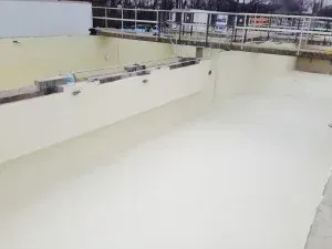 Large, light-colored industrial pool, possibly for water treatment. Long, rectangular shape with white walls and water.