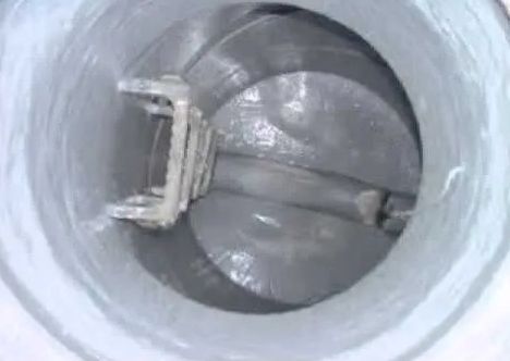 Inside view of a cylindrical structure with a rotating screw conveyor mechanism, coated in a light gray material.
