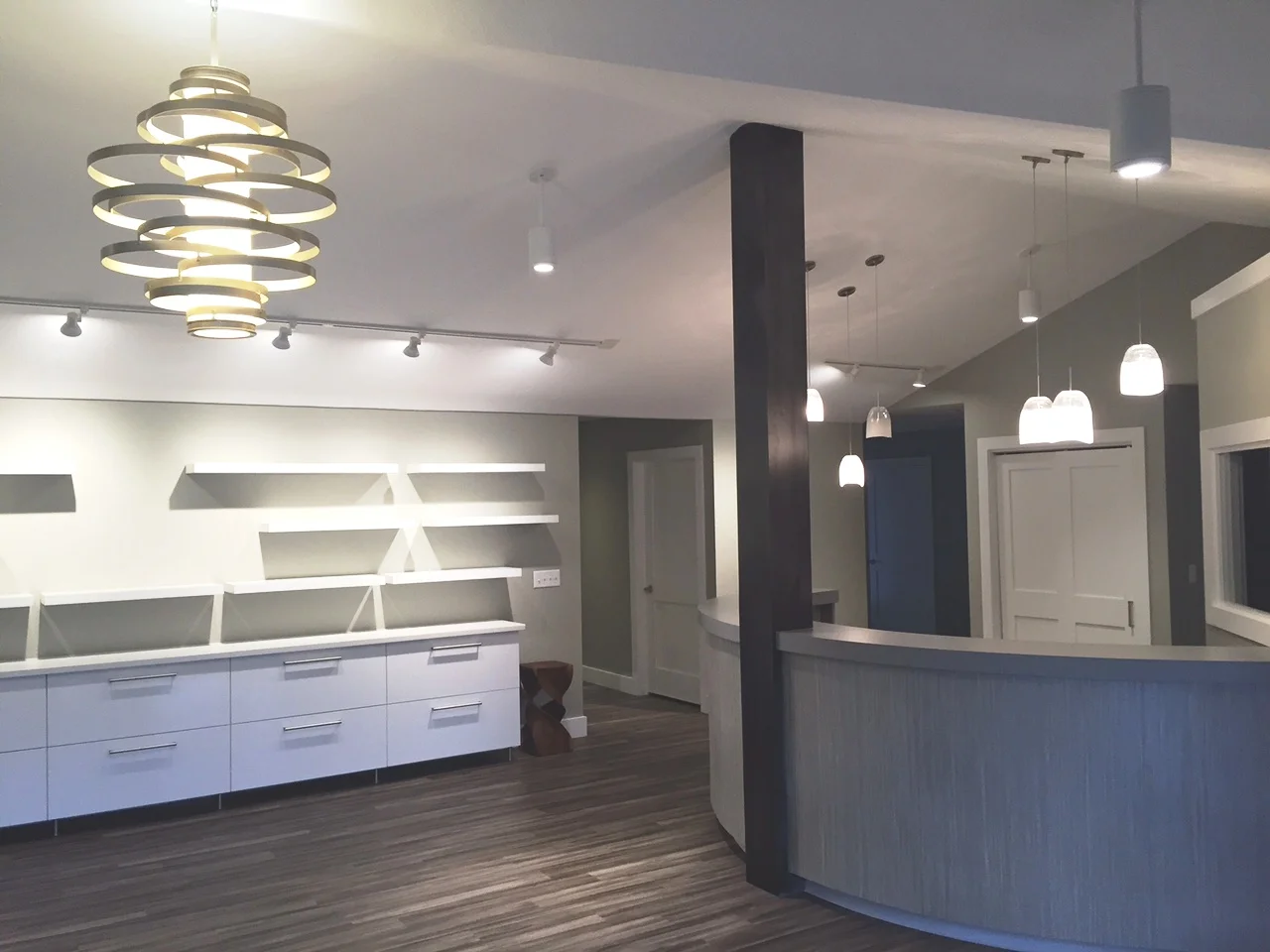 Modern interior with white cabinetry, shelves, and lighting. Dark floor and accent wall.