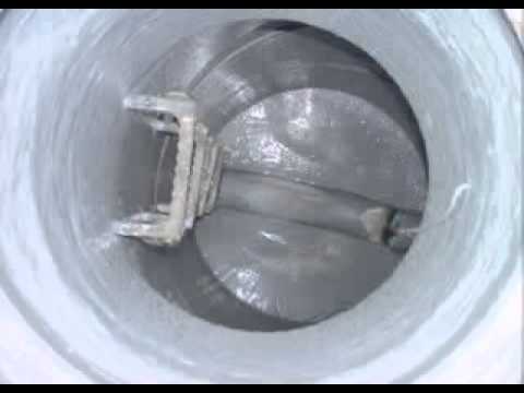 Inside a cylindrical tank, a mixing arm is visible. The interior is coated with a light-colored substance.