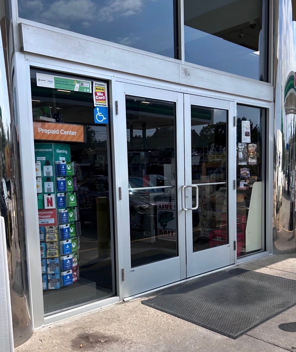 Storefront with glass double doors, snack display, and reflections on the windows.
