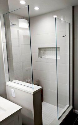 Modern shower with glass walls, gray tiled walls, recessed shelf, and built-in bench.