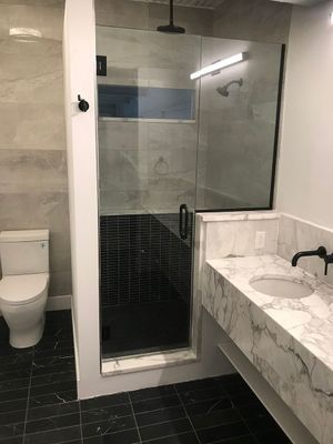 Modern bathroom with shower, toilet, and double sink vanity. Black and white color scheme.