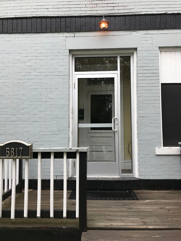 Gray brick building entrance with a white door, and porch. Address sign 5317.