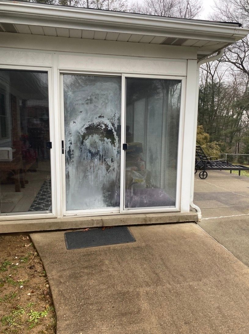 A white exterior wall featuring a sliding glass door with a large, patterned area of shattered or fogged glass.