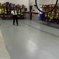 A man is standing in a fire station holding a hose.