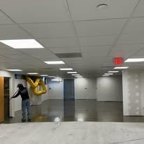 A man is standing in an empty room with a yellow sculpture on the wall.